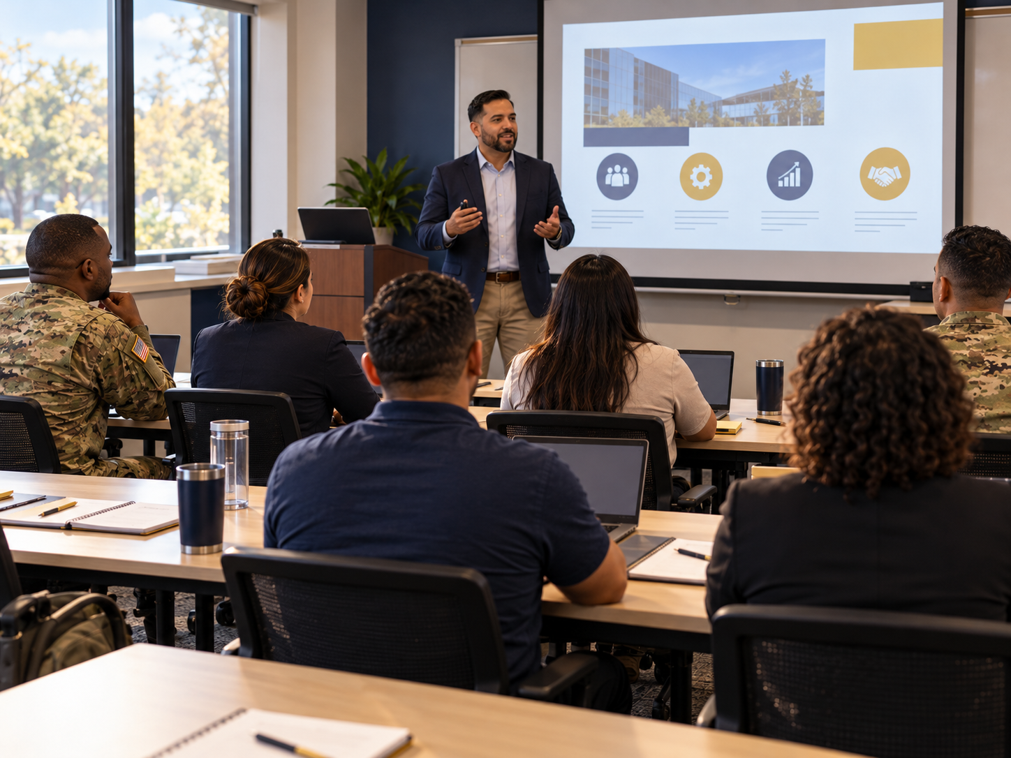 Business professional speaking to adult students in uniforms and business casual in a small classroom
